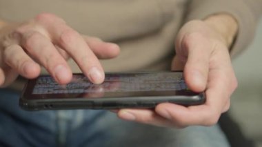 A mans finger touches a monitor to scroll a page on a mobile phone. Viewing photos and documents in the smartphone library. A man in his hands uses a smartphone, turns pages.