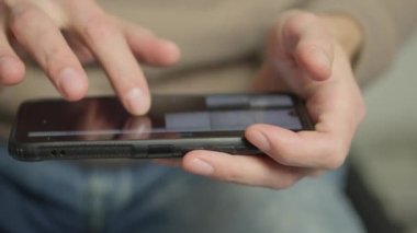 A mans finger touches a monitor to scroll a page on a mobile phone. Viewing photos and documents in the smartphone library. A man in his hands uses a smartphone, turns pages.