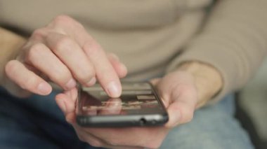 A mans finger touches a monitor to scroll a page on a mobile phone. Viewing photos and documents in the smartphone library. A man in his hands uses a smartphone, turns pages.