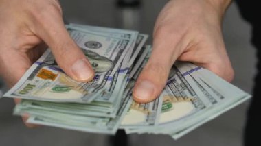 Close-up of male hands counting a stack of US hundred dollar bills. Businessman counts cash. concept of investment, money exchange, credit and deposit. Salary to employees for work.