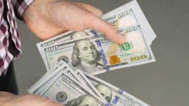 Close-up of male hands counting a stack of US hundred dollar bills. Businessman counts cash. concept of investment, money exchange, credit and deposit. Salary to employees for work.