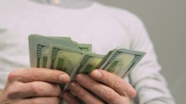 Close-up of male hands counting a stack of US hundred dollar bills. Businessman counts cash. concept of investment, money exchange, credit and deposit. Salary to employees for work.
