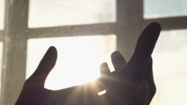 Human hand on background of sun. Backlight silhouette sunlight at sunset sunrise. The concept of love, dream, religion, faith in god, prayer, meditation. Christian Muslim raises his hands to the sky.