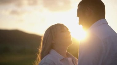 On Valentines Day, a boy and a girl in love walk, hug, relax in nature. Happy couple having fun against sunset background. Holding hands while watching the sunrise.