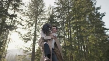 Young couple on walk in park in the spring. A romantic meeting of a happy boy and girl on vacation in the forest. Love and relationship between a man and a woman. Smiles, hugs and emotions at sunset.