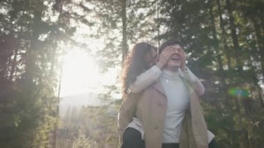Young couple on walk in park in the spring. A romantic meeting of a happy boy and girl on vacation in the forest. Love and relationship between a man and a woman. Smiles, hugs and emotions at sunset.
