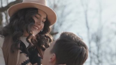 Young couple on walk in park in the spring. A romantic meeting of a happy boy and girl on vacation in the forest. Love and relationship between a man and a woman. Smiles, hugs and emotions at sunset.