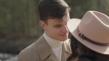 Young couple on walk in park in the spring. A romantic meeting of a happy boy and girl on vacation in the forest. Love and relationship between a man and a woman. Smiles, hugs and emotions at sunset.