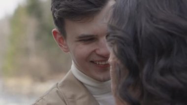 Young couple on walk in park in the spring. A romantic meeting of a happy boy and girl on vacation in the forest. Love and relationship between a man and a woman. Smiles, hugs and emotions at sunset.