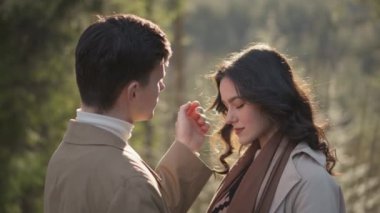 Young couple on walk in park in the spring. A romantic meeting of a happy boy and girl on vacation in the forest. Love and relationship between a man and a woman. Smiles, hugs and emotions at sunset.