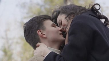 Young couple on walk in park in the spring. A romantic meeting of a happy boy and girl on vacation in the forest. Love and relationship between a man and a woman. Smiles, hugs and emotions at sunset.