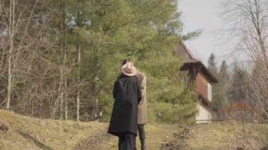 Young couple on walk in park in the spring. A romantic meeting of a happy boy and girl on vacation in the forest. Love and relationship between a man and a woman. Smiles, hugs and emotions at sunset.