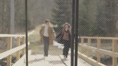 Boy and girl running on wooden bridge over river in mountains. Happy carefree young couple man and woman having fun, romantically and actively resting, joyfully spending time together in relationship.