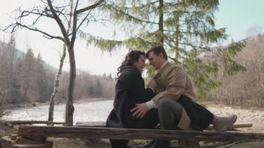 Joyful young couple flirt near river in park. Girl and boy resting in nature. Happy man woman in forest having fun, spending time together. Concept relationship, love, dating in spring, summer, autumn