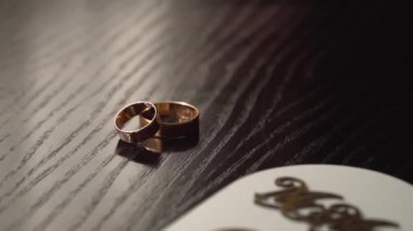 Elegant wedding rings for the bride and groom on a wooden background with reflections. Gold wedding rings. Jewelry and decorations. Near background and selective focus.