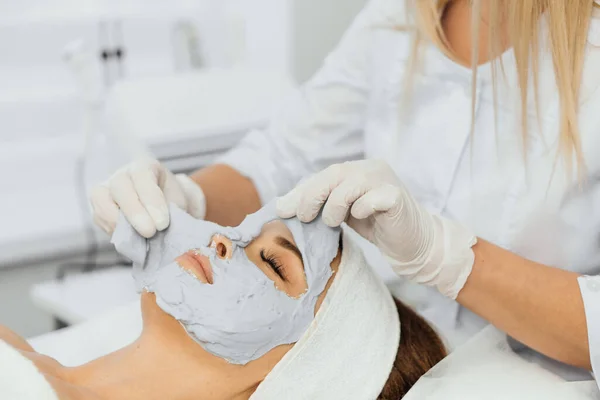 Cosmetic beauty mask for face in beauty salon. Spa procedures, relaxation and skin care. A woman receives facial care from a cosmetologist in a spa salon.