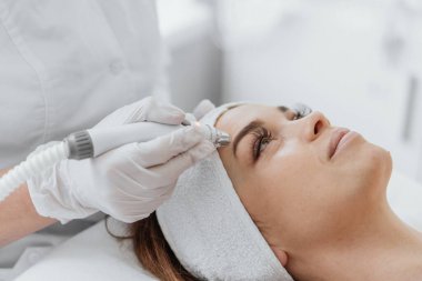 Radiofrequency facial skin lifting. Hardware cosmetology RF lifting procedure and hardware facial massage. Rejuvenation, skin care in a beauty salon. Woman doctor cosmetologist and girl in spa clinic.