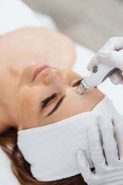 Radiofrequency facial skin lifting. Hardware cosmetology RF lifting procedure and hardware facial massage. Rejuvenation, skin care in a beauty salon. Woman doctor cosmetologist and girl in spa clinic.