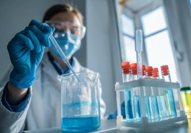 Tıbbi araştırma laboratuarı. Bir bilim adamı pipet ve test tüpüyle çalışır. Biyoteknoloji, kimya, biyokimya ve deneyler alanındaki tıp ve araştırmaların geliştirilmesi.