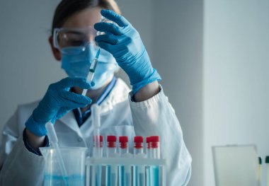 Doktor şırıngayı ilaçla doldurur. Hastane laboratuvarında bir hemşire iğneye hazırlanıyor. Konsept: tedavi, yardım, aşı, aşı, aşı, sağlık, ilaç, tıbbi laboratuvar.