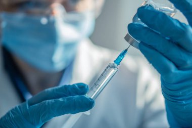 Doktor şırıngayı ilaçla doldurur. Hastane laboratuvarında bir hemşire iğneye hazırlanıyor. Konsept: tedavi, yardım, aşı, aşı, aşı, sağlık, ilaç, tıbbi laboratuvar.