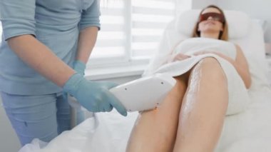 Kozmetik güzellik salonunda lazer tüy çıkarma prosedürü. Kadın kozmetikçi vücut kıllarını alıyor. Güzellik kliniğinde profesyonel estetik cilt bakımı. Yumuşak ve yumuşak tenli eller ve kılsız ayaklar