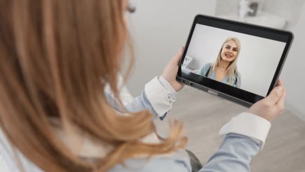 医者はタブレットを通して患者にオンラインで相談する 遠隔医療支援 女性と医療従事者の間のビデオ通信 隔離中の医療のデジタル変換 — ストック動画