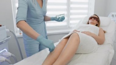 Kozmetik güzellik salonunda lazer tüy çıkarma prosedürü. Kadın kozmetikçi vücut kıllarını alıyor. Güzellik kliniğinde profesyonel estetik cilt bakımı. Yumuşak ve yumuşak tenli eller ve kılsız ayaklar
