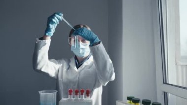 Video parçası, tıbbi sorunları araştırmak ve yeni tedavi yöntemleri geliştirmek için gelişmiş teknolojilerin kullanıldığı büyüleyici bir deneyi gösteriyor. Dişi bir bilim adamı pipeti test tüpü topluyor.