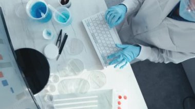 Laboratuvardaki bilimsel araştırma verilerinin analizi, yeni eğilimleri belirlemek ve gelecekteki sonuçları tahmin etmek amacıyla yapılmıştır. Bir bilim adamı monitörün başına oturur ve klavyeye yazı yazar. Yüksek kalite 4k görüntü