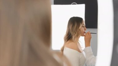 Makyaj atölyesi, modellerin güzellik ve yaratıcılıkla dolu gerçek bir resme dönüştüğü sanat görüntüleri yaratıyor. Bir makyöz, aynanın önünde yansıyan bir kadına dudak çeker.