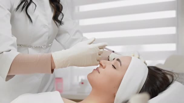 ボツリヌス療法は しわを減少させ 顔の皮膚のトーンを増加させるために薬の注射 若返りの方法です 美容室の若い女性のためのレセプションで美容師 — ストック動画