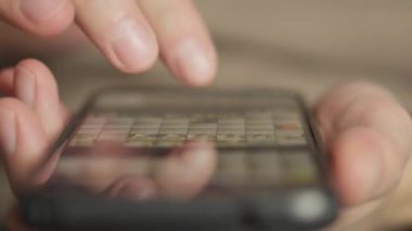 Erkek eli akıllı telefonu yakın plan kullanır, sayfaları kaydırır ve çevrimiçi içeriği tarar. İnternet ve sosyal medya teknolojilerini kullanarak mobil cihazını elinde tutan bir adam. Yüksek kalite 4k