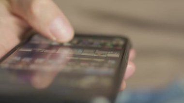 Akıllı telefonunu elinde tutan, sayfaları kaydıran ve dijital teknolojiyi iletişim ve eğlence için kullanan bir adam. Çerçevesinde akıllı telefon olan erkek elleri: Fotoğrafları ve videoları görüntüler