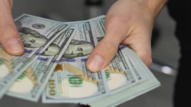 Mali dengesine güvenen bir adam yüz dolarlık banknotlar sayar. Finans piyasasında döviz değişimi. Bu video parçasında ifade edilen güvenilirlik ve başarıdır.