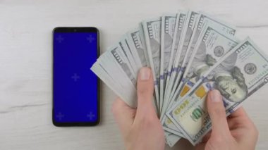 Banknotlu yeşil ekranın arka planında bir akıllı telefonun görüntüsü finans piyasası ve yatırımlarla ilgili projeler için harikadır. Yüksek kalite 4k görüntü