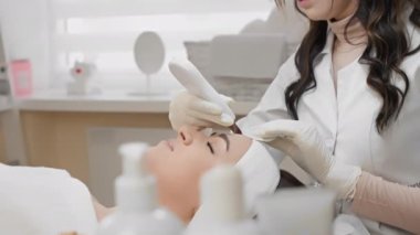 Profesyonel bir kozmetik uzmanı yüz temizleme ameliyatını yüz derisinin sağlığını ve güzelliğini korumak için güvenli ve etkili bir yöntem olarak kullanır. Güzellik salonunda güzel bir kadın manzarası. Gençleştirme