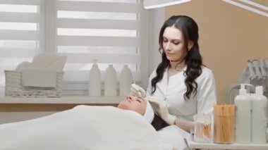 Güzellik salonunda bir güzellik uzmanı tarafından yapılan profesyonel bir yüz bakımı işlemi olan derin yüz temizleme sağlık ve gençlik görüntüsü elde etmek için. Kozmetik kliniğinde genç bir kadın.