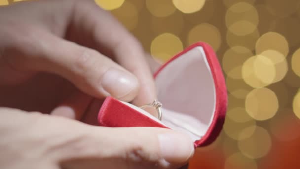 一个男人从一个红色礼品盒里拿出一枚金戒指 手把钻石戒指放在棺材里 求婚的概念 送给心爱的未来妻子的礼物高质量的4K镜头 — 图库视频影像