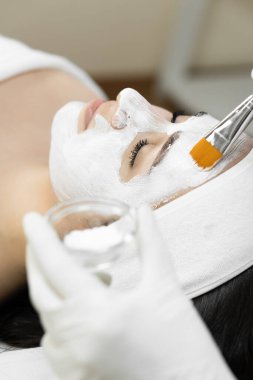 Güzelliğin dokunuşu: Bu fotoğraf kozmetik bir maskenin ciltte nasıl yumuşak ve yumuşak bir güzellik dokunuşu yarattığını gösteriyor, onu daha çekici ve sağlıklı kılıyor. Güzellik kliniğindeki kadın. Yüksek