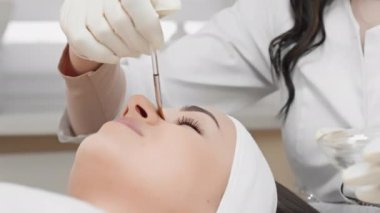 Profesyonel bir kozmetik uzmanı cilt soyma prosedürü uygular, eski katmanların derilerinin soyulmasını sağlar ve genç ve ışıl ışıl bir görünüm için canlandırıcı bir yenileme sağlar. Güzellik kliniğindeki kadın