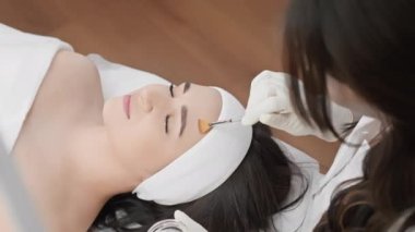 Bu videoda, yüz derisinin soyulmasının kozmetik prosedürü sağlıklı cilde yapılan bir yolculuktur, güzellik uzmanının her hareketi doğal yumuşaklığını ve gençliğini geri kazanmasına yardımcı olur. Güzellik salonundaki kadın.