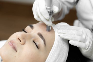 Fotoğraf, güzellik kliniğindeki kozmetik uzmanının profesyonelliğini ve deneyimini vurgulayarak kısmi mezoterapi anını aktarıyor. Doktorun resepsiyonundaki güzel kız.
