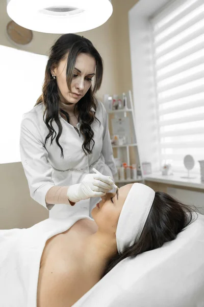 Remove wrinkles, leave beauty: a woman on the procedure of butolinotherapy, on an excellent facial procedure for rejuvenation and restoration of facial skin in a beauty clinic. High quality photo