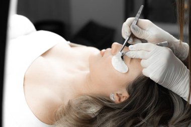 Fotoğraf, kozmetikçide kirpik uzatma sürecinin detaylarını gösteriyor. Her kirpik maksimum özen ve beceriyle kadına bir güzellik salonunda enfes bir görünüm kazandırır.