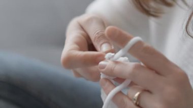 Bir kadın kışın evde iplikten kalın elbiseler örer. Sonbahar ve bahar için örülmüş sıcak kıyafetler. Kadınların elleri, yakın plan. İğne işi ve hafta sonları serbest iş. Yararlı bir şekilde dinlen. Yüksek