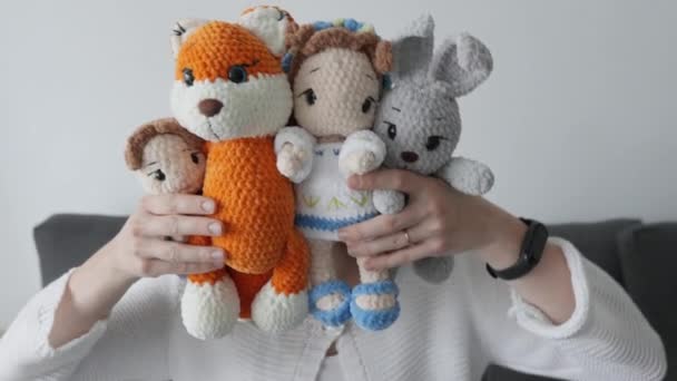 一位可爱的女工匠拍摄了一段视频 展示她为孩子们制作的不同寻常的针织羊毛衫软玩具 一个做小生意的年轻女人手里拿着钱 兔子和娃娃 — 图库视频影像