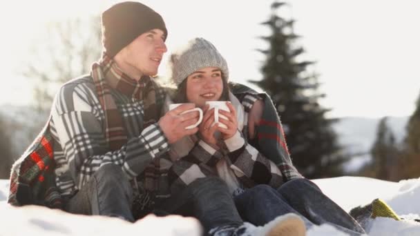 冬の魔法とロマンスを捉えた魅惑的なショットで カップルは忘れられない瞬間を一緒に体験します 手と冬の風景の中に暖かい飲み物のカップを持つ陽気なカップル — ストック動画