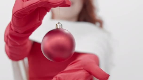 一个身穿红色衣服 背带白色围巾的女人手里拿着一颗红色气球圣诞树的装饰品 一个戴着红色手套的快乐姑娘手里拿着圣诞树玩具 — 图库视频影像
