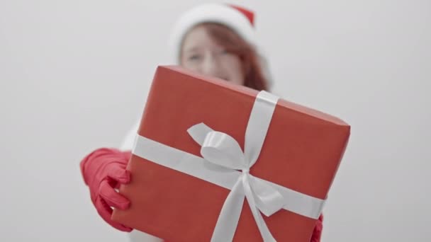 このビデオは お祝いの喜びと期待を伝えるもので 熱意を持った女性が白い背景に手を差し伸べる贈り物を持っていることを示しています サンタからの冬の休日のための贈り物 — ストック動画